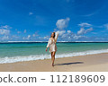 Young woman walks barefoot on the beach 112189609