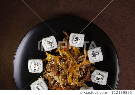 top view Japanese cuisine, rice rolls with sesame seeds and soy sauce on a black plate 112189856