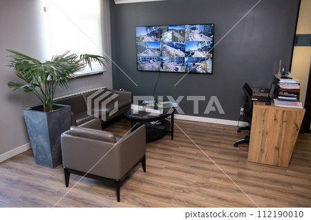 Modern office interior with dark walls and leather furniture, monitor on the wall Modern office interior with dark walls and leather furniture, monitor on the wall 112190010