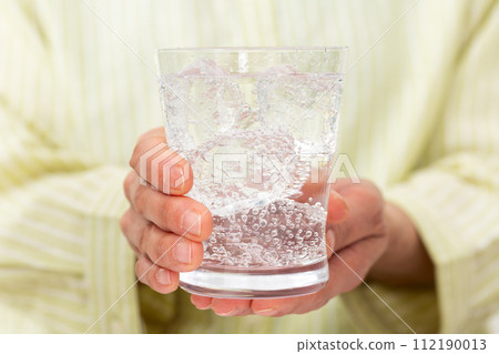 Hand of a woman drinking carbonated water Hand of a woman drinking carbonated water 112190013