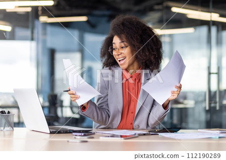 A focused businesswoman is intently reviewing multiple papers in a bright, contemporary office space. The image exudes a sense of professionalism, concentration, and determination at the workplace. A focused businesswoman is intently reviewing multiple papers in a bright, contemporary office space. The image exudes a sense of professionalism, concentration, and determination at the workplace. 112190289