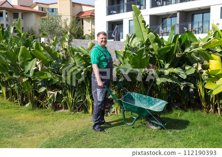 Man father husband cleaning the area near the house collecting garbage in a cart Man father husband cleaning the area near the house collecting garbage in a cart 112190393