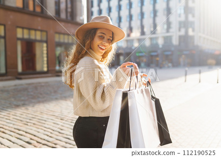 Stylish woman in trendy clothes with shopping bags near mall. Black friday, discounts, sale concept. Stylish woman in trendy clothes with shopping bags near mall. Black friday, discounts, sale concept. 112190525