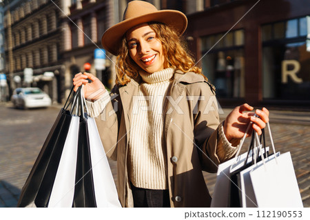 Stylish woman in trendy clothes with shopping bags near mall. Black friday, discounts, sale concept. 112190553