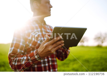Farmer working with digital tablet in field at sunset. Checking wheat field. Agriculture concept. 112190736