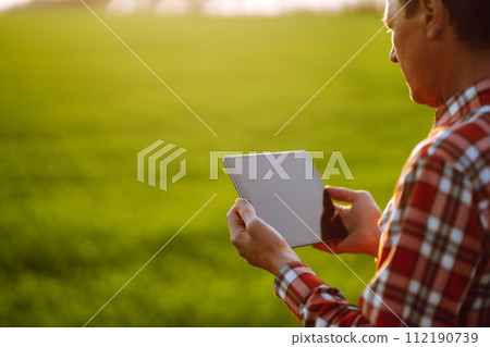 Farmer working with digital tablet in field at sunset. Checking wheat field. Agriculture concept. 112190739