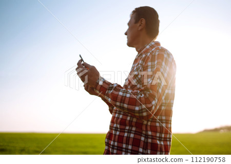 Farmer working with digital tablet in field at sunset. Checking wheat field. Agriculture concept. 112190758