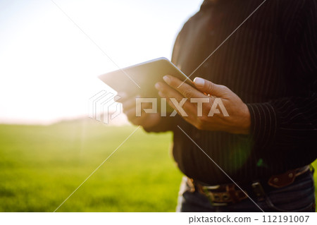 Farmer owner using touchpad for check wheat field at sunset. Farmer working with digital tablet. Farmer owner using touchpad for check wheat field at sunset. Farmer working with digital tablet. 112191007