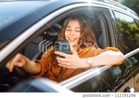 Beautiful woman driver in a car with a phone in her hands. Leisure, travel, technology, navigation. Beautiful woman driver in a car with a phone in her hands. Leisure, travel, technology, navigation. 112191298