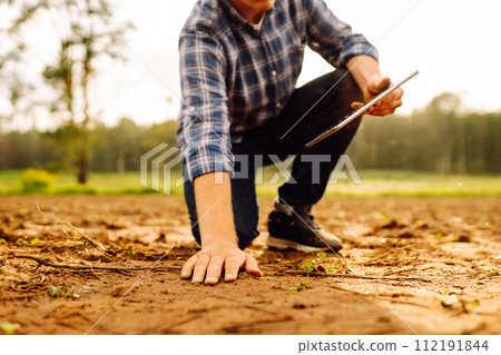 The farm owner's hand touches soil, checks quality of the soil before sowing. Ecology, technology. 112191844