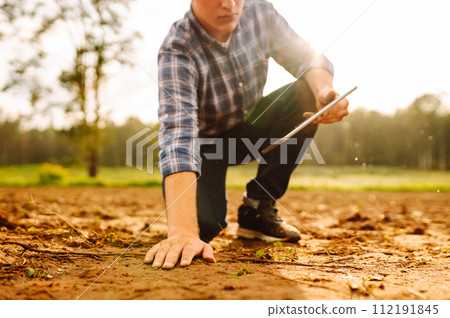 The farm owner's hand touches soil, checks quality of the soil before sowing. Ecology, technology. 112191845