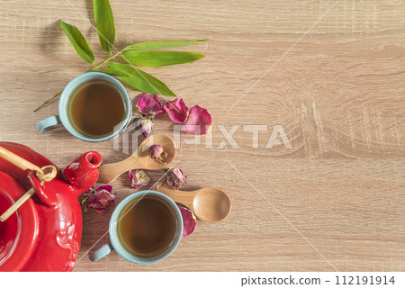 Chinese tea time concept; two chinese cups and roses petals on a wooden background; copy space Chinese tea time concept; two chinese cups and roses petals on a wooden background; copy space 112191914