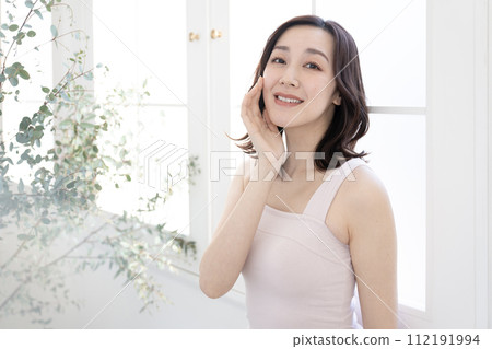 Beauty Woman putting her hand on her cheek by the window Beauty Woman putting her hand on her cheek by the window 112191994