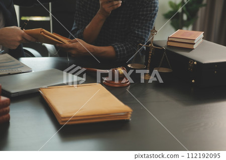 Justice and Law concept. Legal counsel presents to the client a signed contract with gavel and legal law or legal having team meeting at law firm in background 112192095