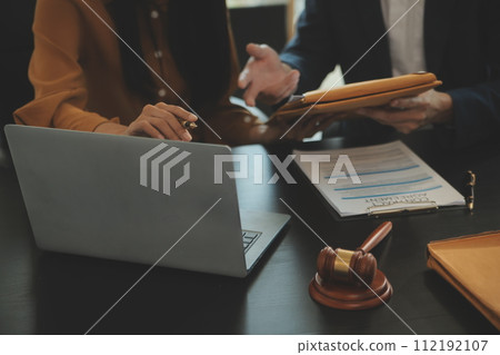 Justice and Law concept. Legal counsel presents to the client a signed contract with gavel and legal law or legal having team meeting at law firm in background 112192107