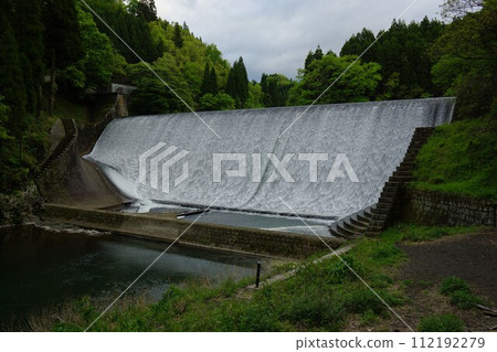 Flowing water overflowing the embankment of Hakusui Dam 112192279