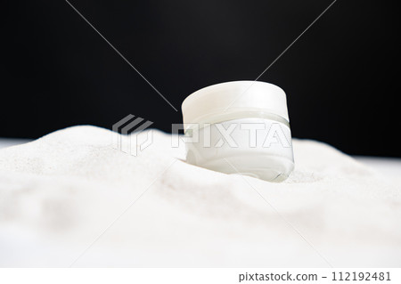Natural eco cosmetics cream in white glass jar on the sand, place for text 112192481