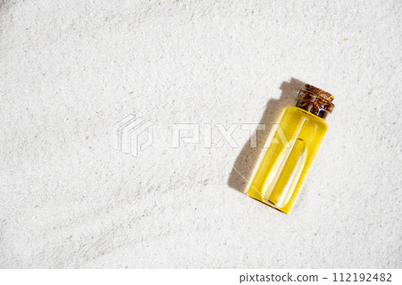 Essential oil in glass bottle on sand, top view, space for text. Essential oil in glass bottle on sand, top view, space for text. 112192482