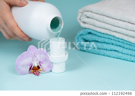 The process of pouring natural eco gel liquid laundry detergent from the bottle into the cap 112192498