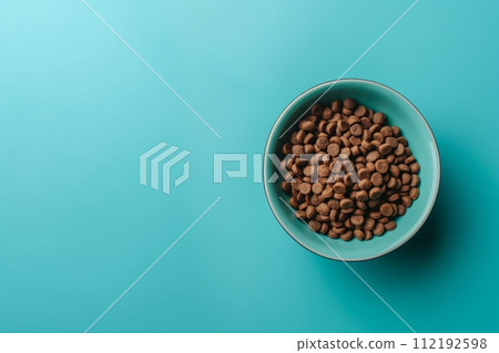 Top view of dry animal feed in blue bowl on a blue background with space for text 112192598