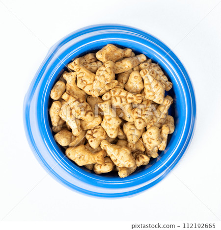 A treat for cats and kittens is a fish-shaped catnip cookie in a blue bowl, copy space for text. 112192665