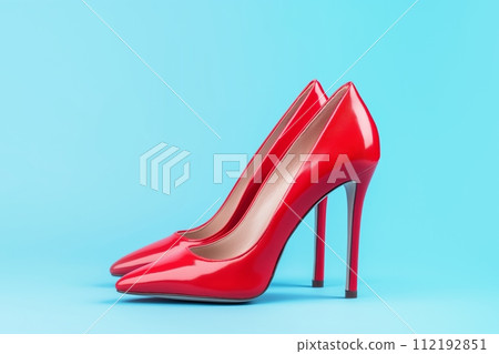 A pair of shiny red high heeled shoes against blue background 112192851