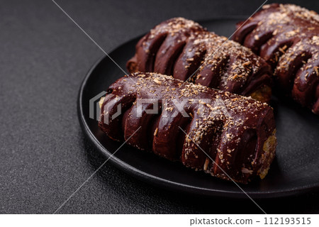 Delicious sweet chocolate cakes with fruit filling and sprinkles on a ceramic plate 112193515