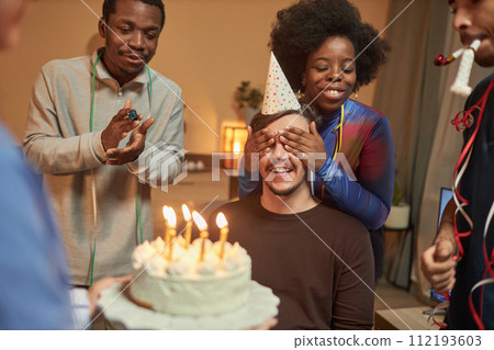 Multiethnic group of friends surprising young man with disability at Birthday party and celebrating together at home 112193603