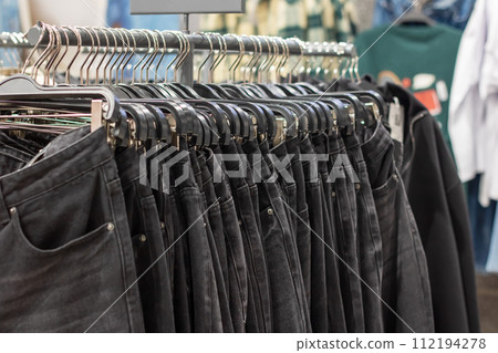 Pants hanging on hangers in a store Pants hanging on hangers in a store 112194278