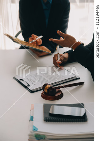 Justice and Law concept. Legal counsel presents to the client a signed contract with gavel and legal law or legal having team meeting at law firm in background 112194468