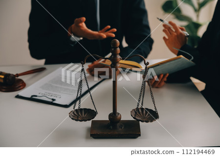 Justice and Law concept. Legal counsel presents to the client a signed contract with gavel and legal law or legal having team meeting at law firm in background 112194469