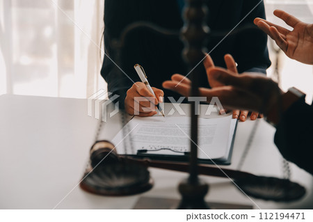 Justice and Law concept. Legal counsel presents to the client a signed contract with gavel and legal law or legal having team meeting at law firm in background 112194471