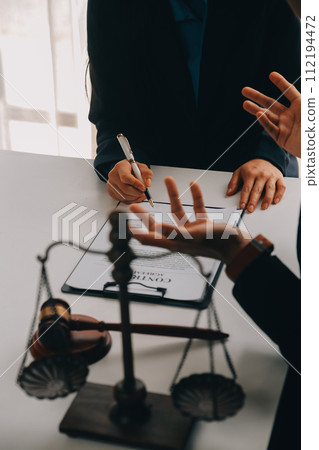 Justice and Law concept. Legal counsel presents to the client a signed contract with gavel and legal law or legal having team meeting at law firm in background 112194472