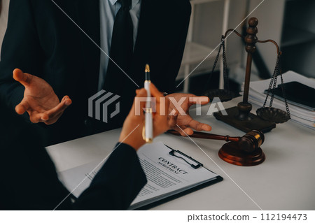 Justice and Law concept. Legal counsel presents to the client a signed contract with gavel and legal law or legal having team meeting at law firm in background 112194473