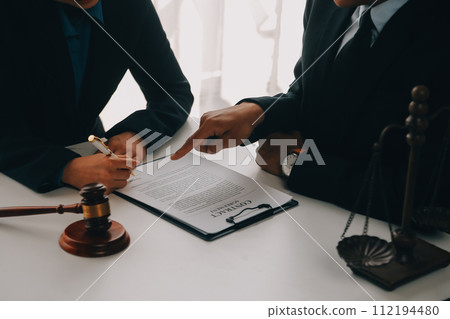 Justice and Law concept. Legal counsel presents to the client a signed contract with gavel and legal law or legal having team meeting at law firm in background Justice and Law concept. Legal counsel presents to the client a signed contract with gavel and legal law or legal having team meeting at law firm in background 112194480
