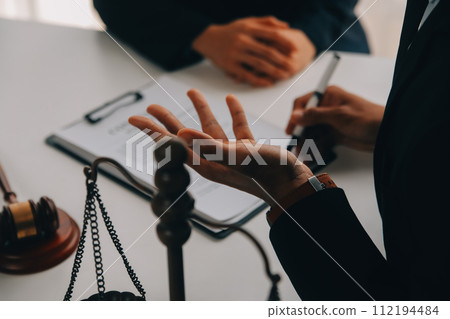 Justice and Law concept. Legal counsel presents to the client a signed contract with gavel and legal law or legal having team meeting at law firm in background 112194484