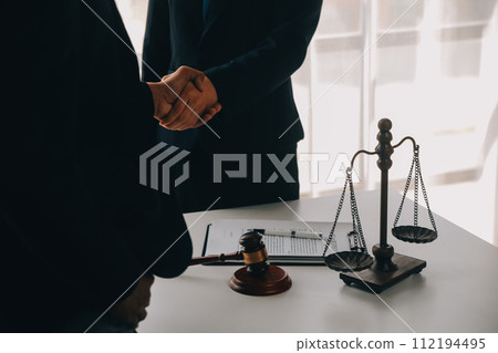 Justice and Law concept. Legal counsel presents to the client a signed contract with gavel and legal law or legal having team meeting at law firm in background 112194495