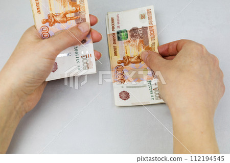 A woman holds a wad of money in her hand. A million Russian rubles in paper money in a woman's hand. Cash savings in Russia. 112194545