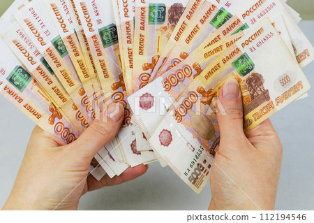 A woman holds a wad of money in her hand. A million Russian rubles in paper money in a woman's hand. Cash savings in Russia. A woman holds a wad of money in her hand. A million Russian rubles in paper money in a woman's hand. Cash savings in Russia. 112194546