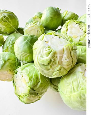 Close up of fresh green Brussels sprouts on white background. Organic vegetable, healthy food, vegan diet concept. Close up of fresh green Brussels sprouts on white background. Organic vegetable, healthy food, vegan diet concept. 112194579