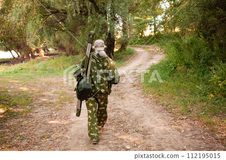man gray-haired fisherman is looking for a place to fish, goes forward, the view from behind. Back. Beautiful forest, river bank, comes home, copy space, outdoor. Walking, hunting. man gray-haired fisherman is looking for a place to fish, goes forward, the view from behind. Back. Beautiful forest, river bank, comes home, copy space, outdoor. Walking, hunting. 112195015