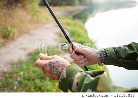 pensioner collects a fishing rod. Instruction, collection process. Copy space, senior concept. Outdoor, beautiful scenery. threads pensioner collects a fishing rod. Instruction, collection process. Copy space, senior concept. Outdoor, beautiful scenery. threads 112195038