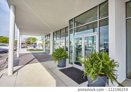 Modern Commercial Building Entrance with Greenery and Reflections 112196259