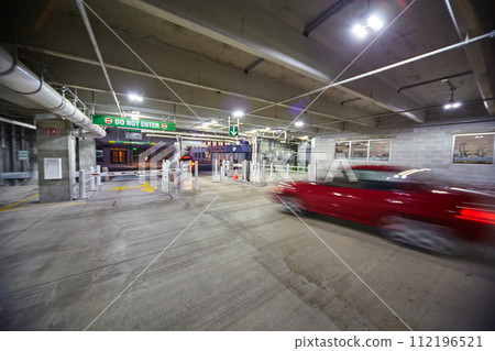 Red Car Speeding in Parking Garage with Green Light - Low Angle View Red Car Speeding in Parking Garage with Green Light - Low Angle View 112196521