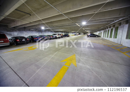 Bright Yellow Arrows in Parking Garage with Fluorescent Lights - Ground View 112196537