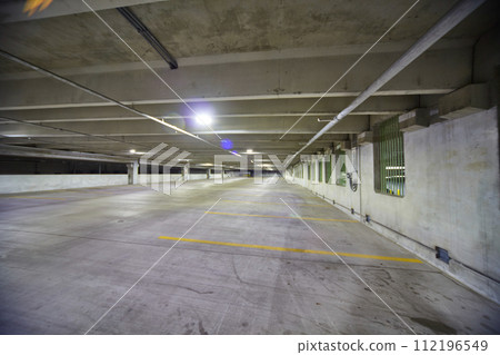 Spacious Empty Parking Garage with Fluorescent Lighting and Green Windows Spacious Empty Parking Garage with Fluorescent Lighting and Green Windows 112196549