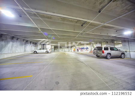 Sparse Indoor Parking Garage with Bright Lights and Two Cars 112196552