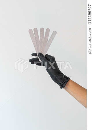 Female hand holds nails files on white background. Concept of polishing nails. Spa treatment beauty. White background with copy space. 112196707