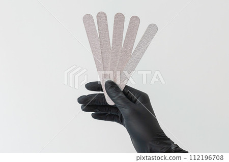 Female hand holds nails files on white background. Concept of polishing nails. Spa treatment beauty. White background with copy space. 112196708