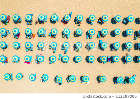 Aerial view of colorful blue umbrellas on sandy beach at sunset Aerial view of colorful blue umbrellas on sandy beach at sunset 112197006